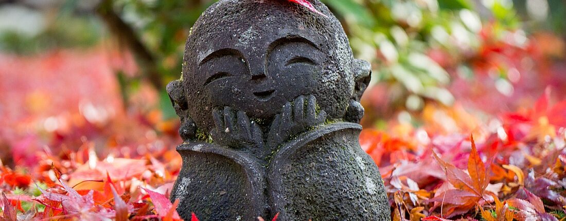 kleine Mönchstatue im Herbstlaub in Japan